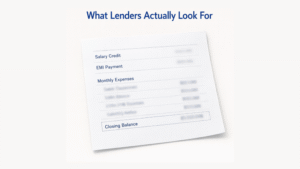 A minimal, editorial-style image of a single bank statement page lying slightly tilted on a soft off-white background. The statement displays blurred text with visible structure, including a "Salary Credit" line, an "EMI Payment" line, a cluster of "Monthly Expenses," and a boxed "Closing Balance" line. At the top, the title “What Lenders Actually Look For” appears in navy blue, sans-serif font. The scene is clean, neutral, and softly lit, with no other objects present.